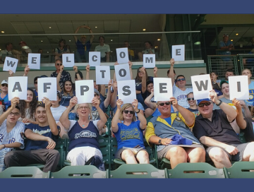 AFP Members in stands at Brewers baseball game holding cards that spell out "Welcome to AFPSEWI"