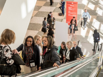 Image of professionals riding up on large escalator in a conference center