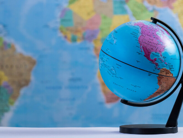 Image of a small globe in the foreground with a wall map in the background