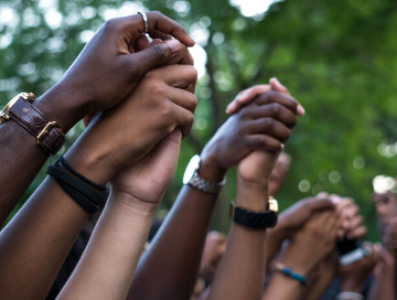 image of arms raised and holding hands during a peaceful protest