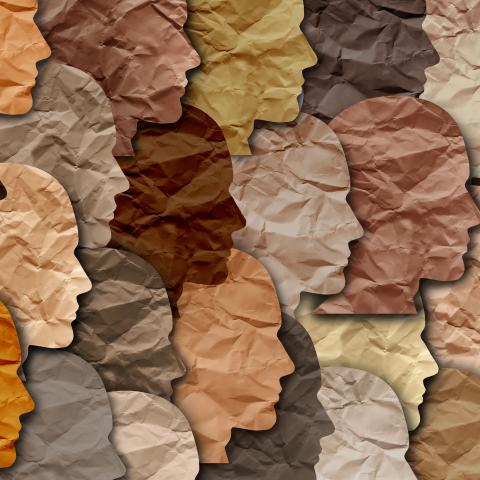 tissue paper cutouts of human head template in a variety of skin tone colors overlapping