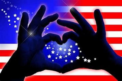 hands depicting a heart in front of USA Flag