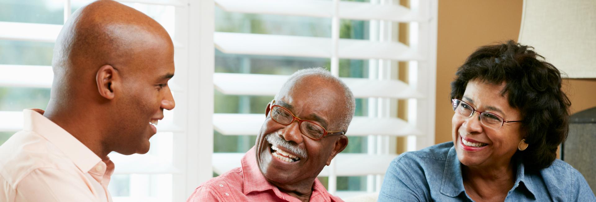 Smiling middle aged black man speaking with smiling older black couple