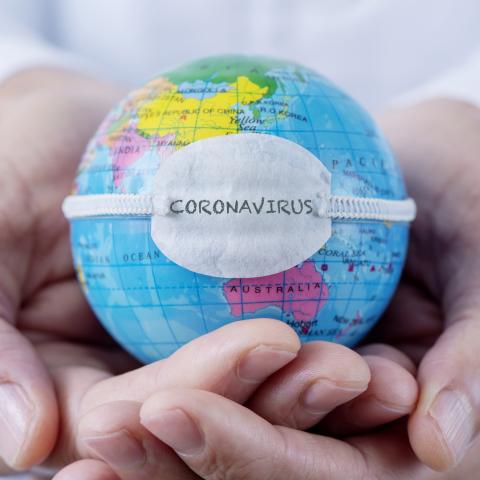 hands holding globe of world with coronavirus mask