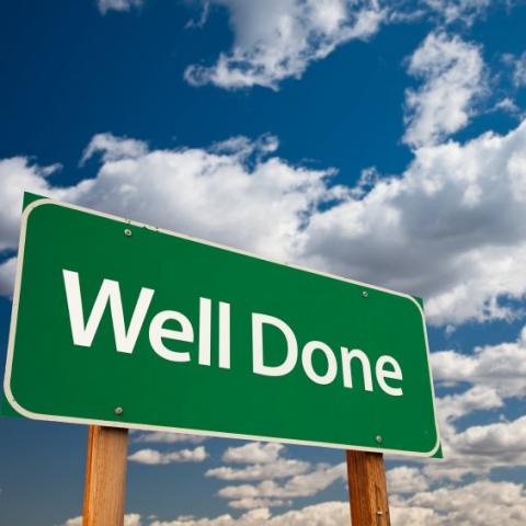 Well done sign with blue cloudy sky behind
