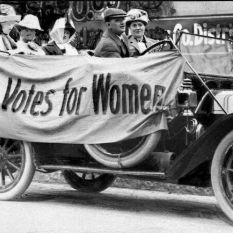 Photo from 1919 of women in old car with banner that reads "Votes for Women"