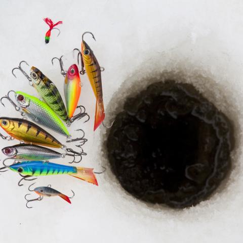 image of ice fishing hole with lures laid out next to it