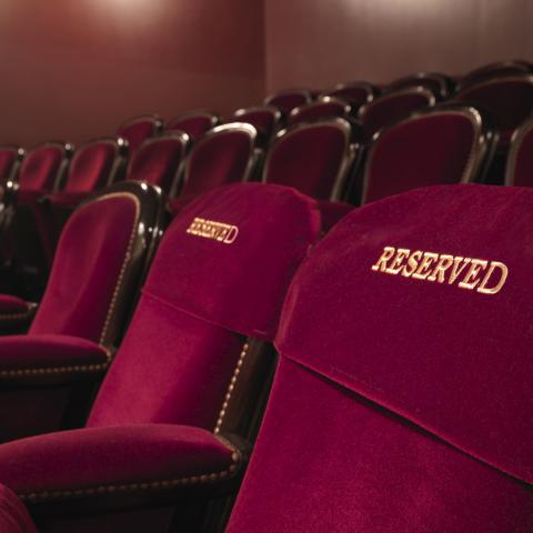 image of a row of red velvet theater seats with "RESERVED" embroidered on them