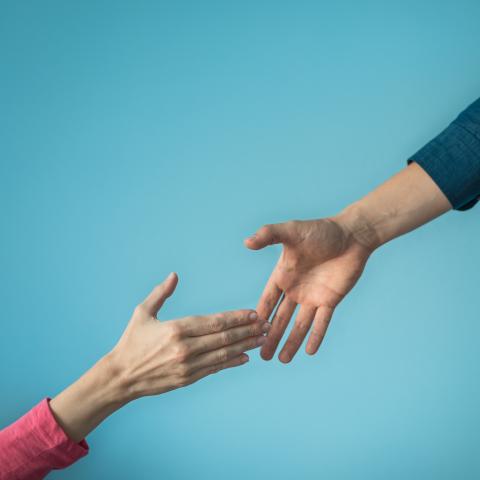 two female hands reaching for each other depicting a "helping hand"