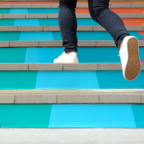 person walking up colorful stairs