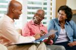 young black professional on a couch visiting with older black couple reviewing documents