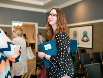 AFP member holding folder with AFP label smiling while talking with other members at an event