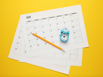image of calendar pages, pencil, and small clock