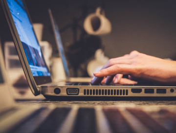 side view of female hands typing on laptop