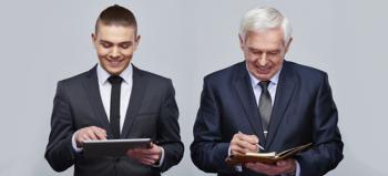 Millennial and seasoned professional both in suits standing together working on their tablet and portfolio