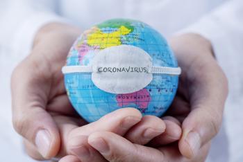 hands holding globe of world wearing "coronavirus" mask