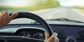 image from driver point of view of steering wheel and road through the windshield