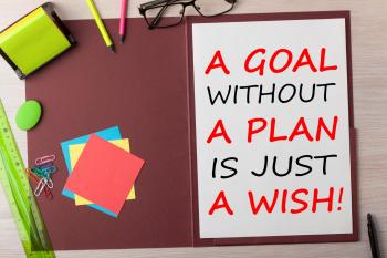 A Goal without a Plan is Just a Wish written in paper sheet on presentation folder and various stationery on wooden table