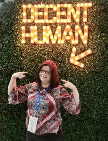 Heather Willette standing under neon sign that says "DECENT HUMAN"