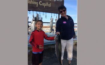 Mary Pat Beals and her grandson holding up a large fish the caught while standing on a fishing pier