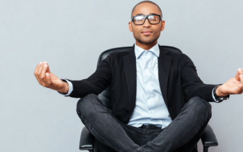 man in suit with legs crossed and arms resting on knees meditating