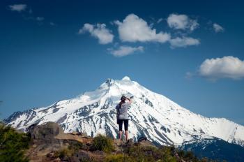 Woman standing looking at snow covered mountain in the distance