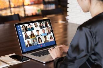 woman at laptop with screen showing fifteen faces of others in the online meeting