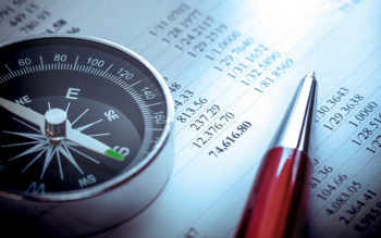 image of a compass and fine pen resting on an accounting ledger