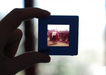 person holding photo slide to the light showing image of older couple in the 1960s