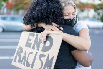 black and white woman hugging. white women holding a sign that says "end racism"