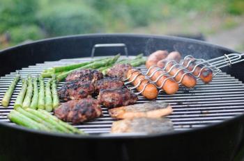 image of grill with asparagus, hamburgers and hot dogs being cooked