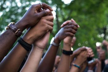 Image of arms raised and hands joined of many protesters of different races