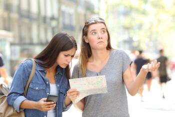 two women holding and looking at map looking confused and lost