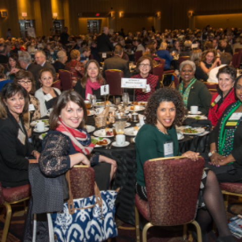 Image of a table of people with many tables of people in the background at an event