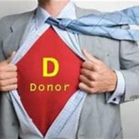 man in suit in tie opening his button down shirt to expose a red shirt that says "D" "donor"
