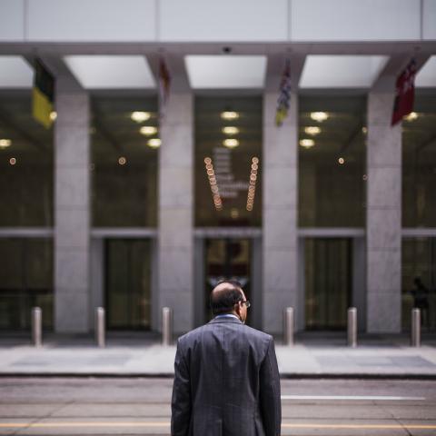 man standing along in front of large corporate building