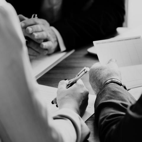 image of couple holding a checkbook and pen sitting across the desk from a man. 