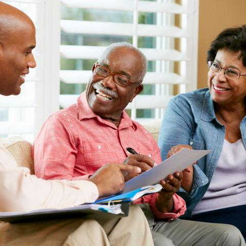 young black professional visiting with older black couple on the couch