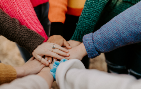 Hands and arms joined together in the center of a circle.
