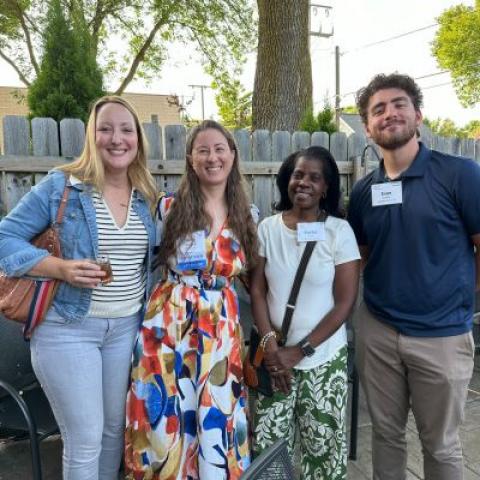 Four people of mixed race, standing on a restaurant patio smling