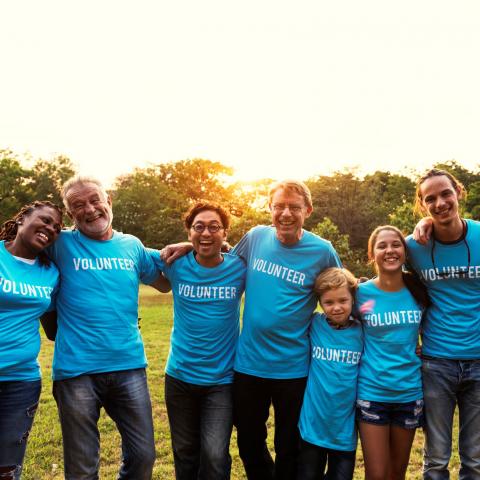 People wearing volunteer shirts with arms around each other