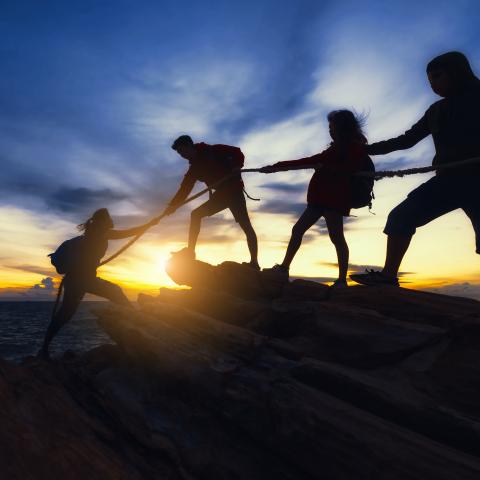 Climbers helping each other reach the top