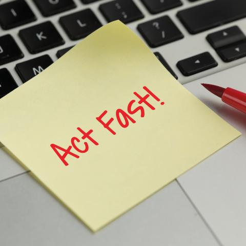 Post-it note on a laptop that says "Act Fast!!"