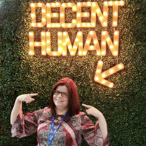 Heather Willette standing under neon sign that says "DECENT HUMAN"