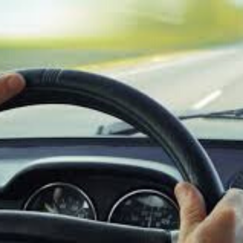 image from driver point of view of steering wheel and road through the windshield