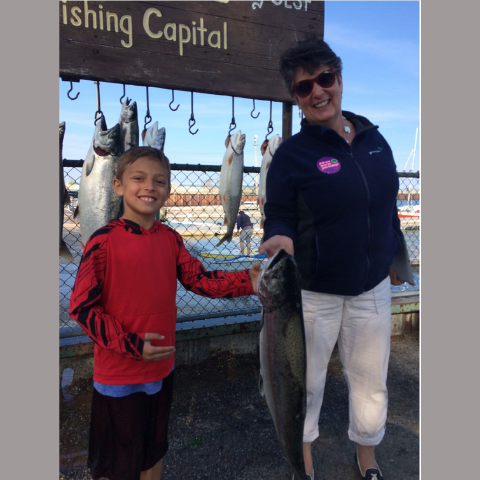 picture of Mary Pat Beals and her grandson holding up a large fish the caught while standing on a fishing pier