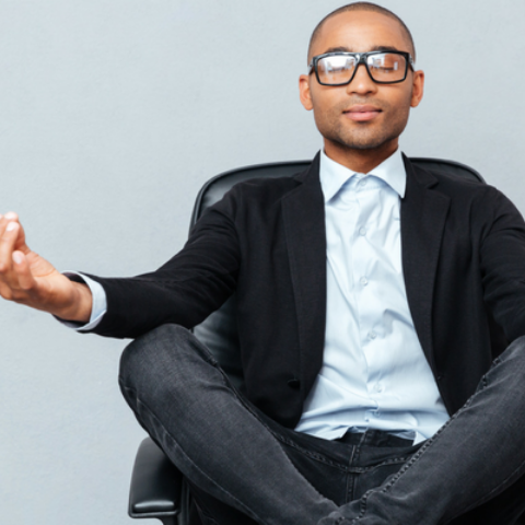 man in suit with legs crossed and arms resting on knees meditating