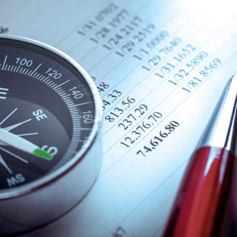 image of a compass and fine pen resting on an accounting ledger