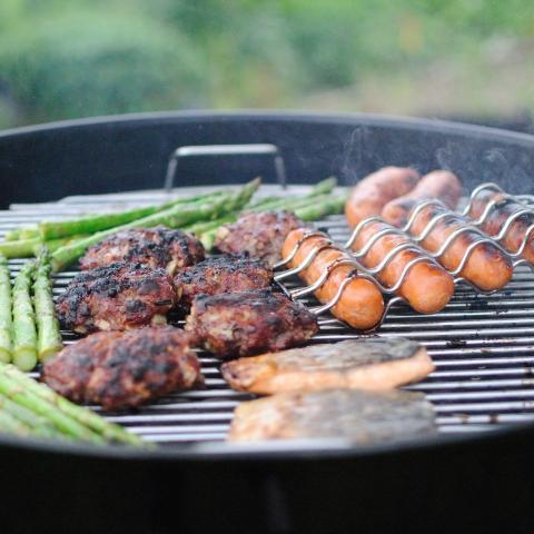 image of grill with asparagus, hamburgers and hot dogs being cooked