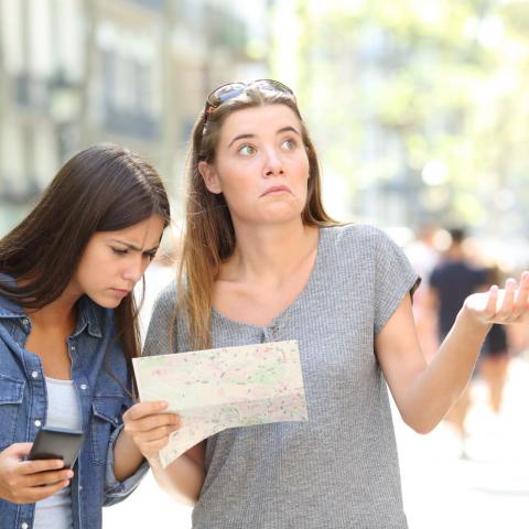 two women holding and looking at map looking confused and lost
